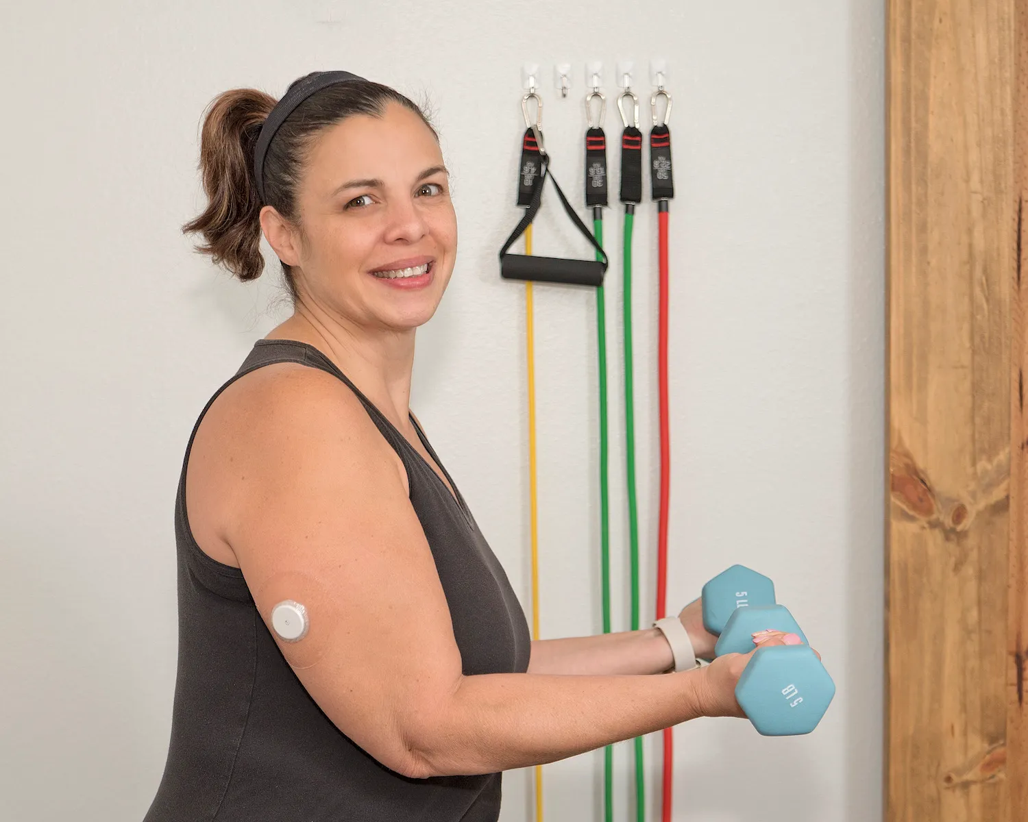 A Nutrisense member holding dumbbell with both hands and having a cgm sensor on her right upper hand.