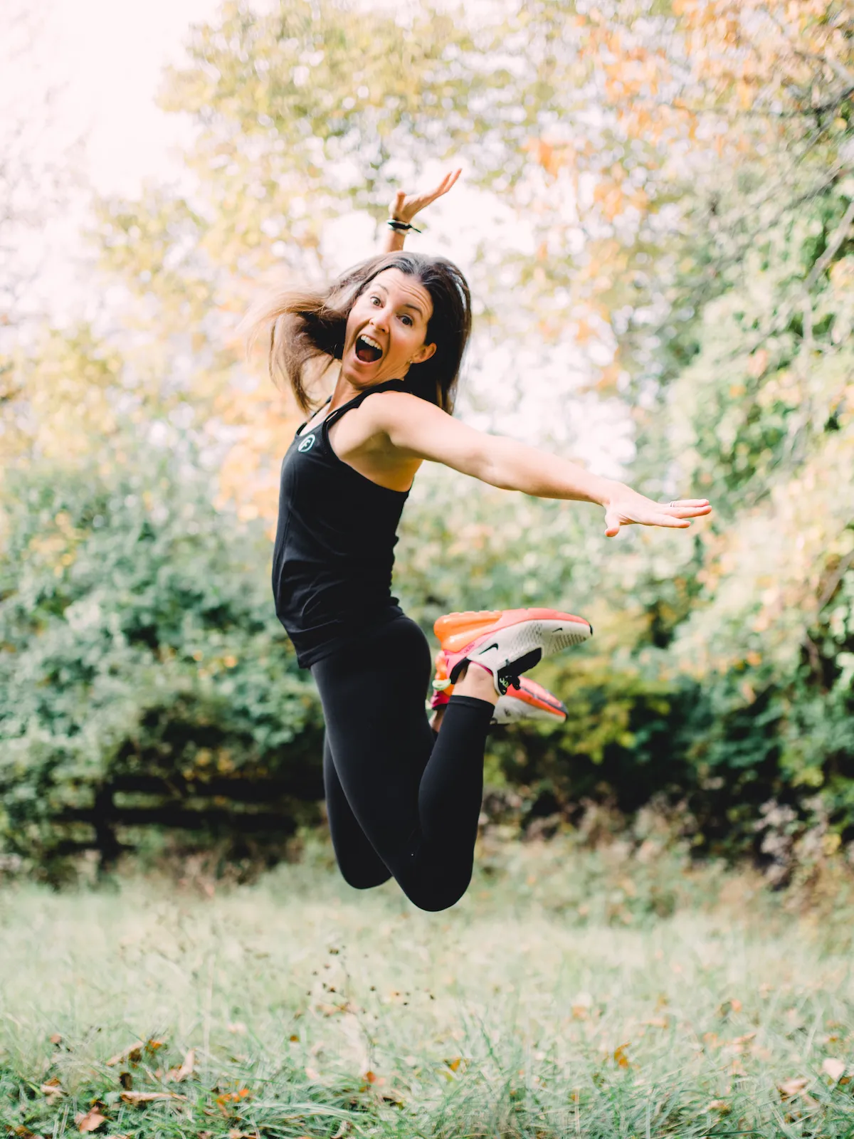 A woman jumped high with her feet behind her back and hands stretched wide aside.