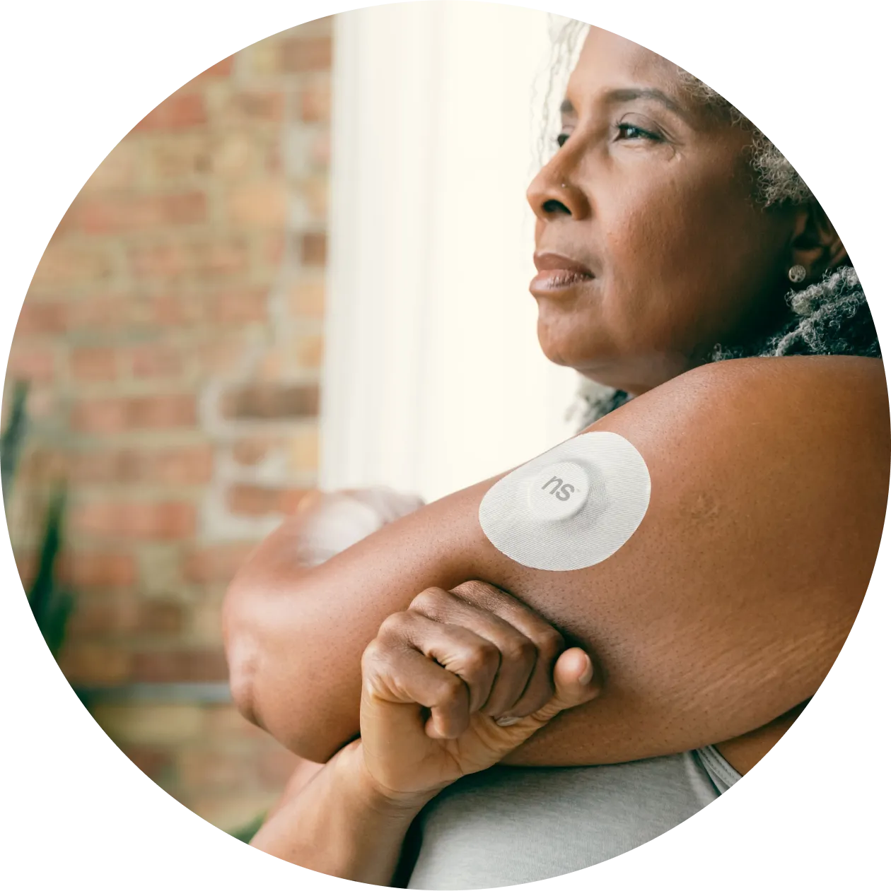 A woman stretches her left shoulder wearing Nutrisense CGM tracking device on her upper left hand available in nutrisense.io