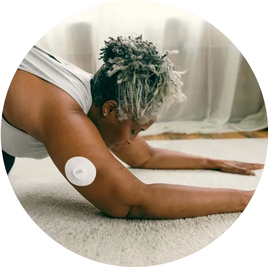 A woman practicing lower body stretches exercise wearing Nutrisense CGM tracking device available in nutrisense.io