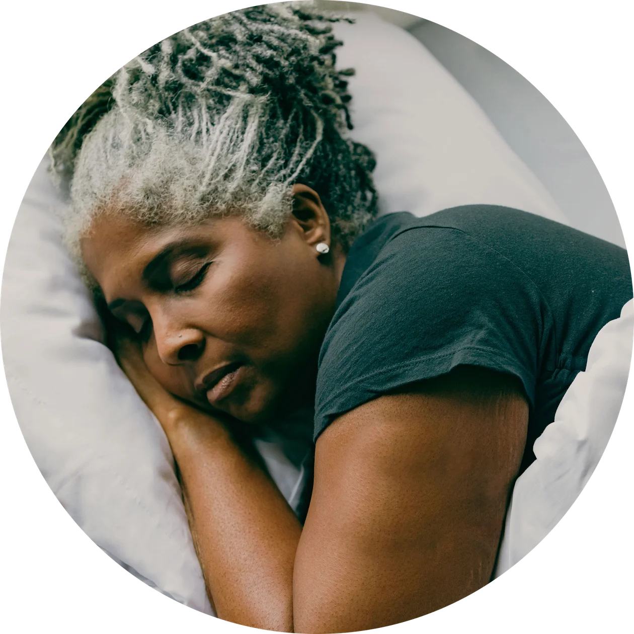 A woman sleeping wearing a green t-shirt with her head on top of bent left hand with a Nutrisense cgm sensor.