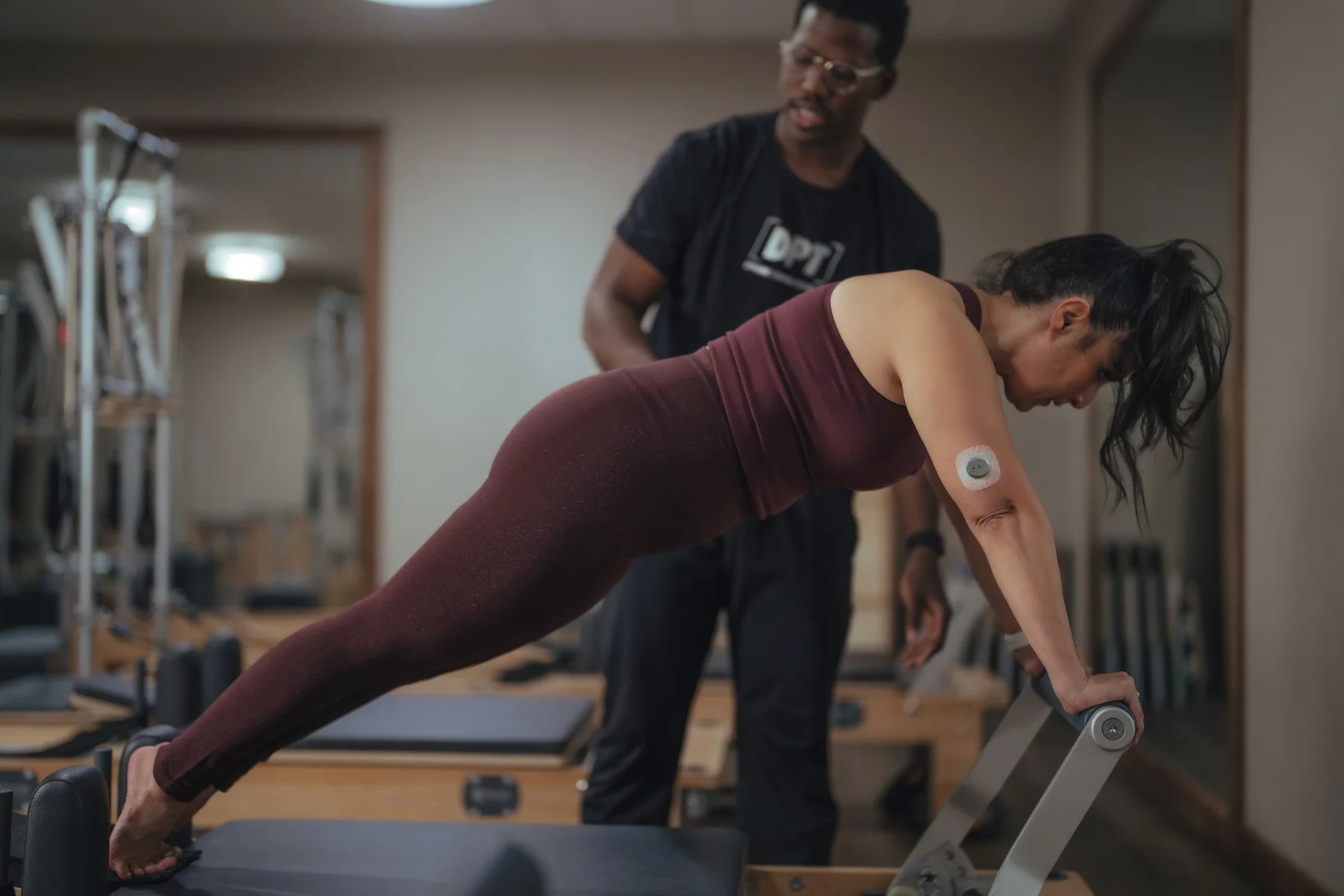 A Nutrisense member sitting down looking at her upper left hand where Nutrisense CGM sensor is located