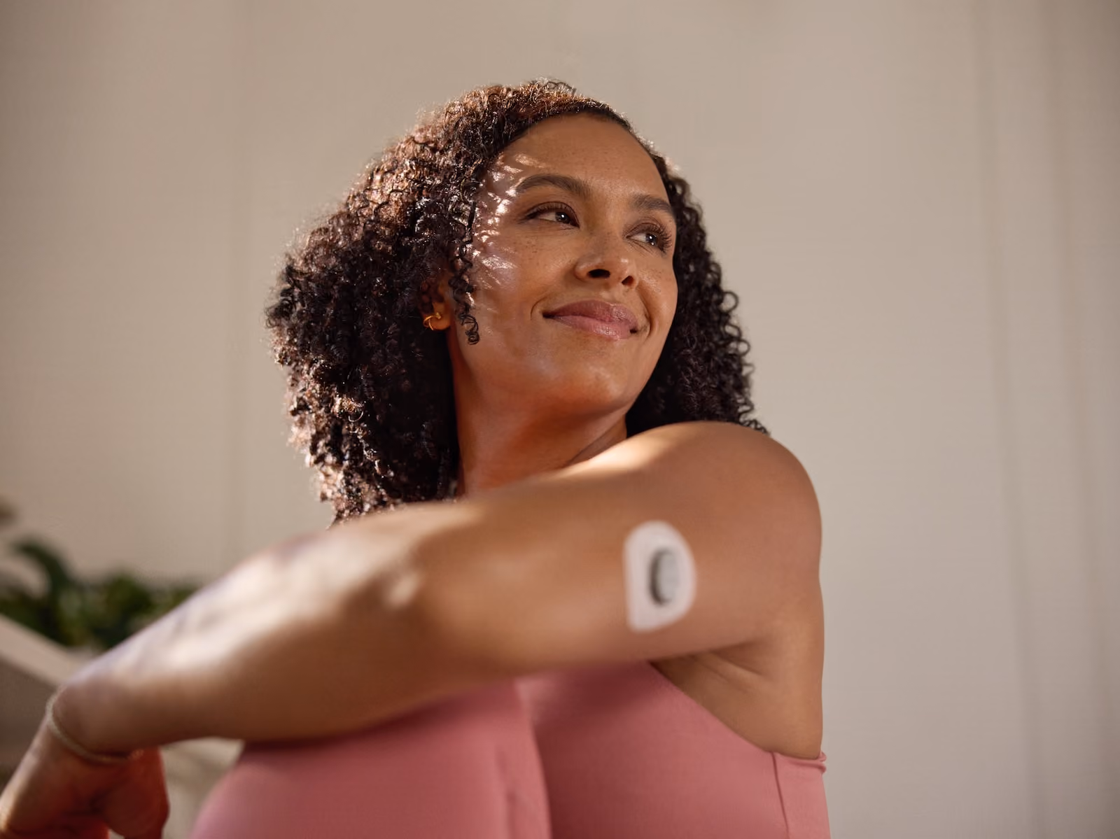 A woman stretches her left shoulder wearing Nutrisense CGM tracking device on her upper left hand available in nutrisense.io