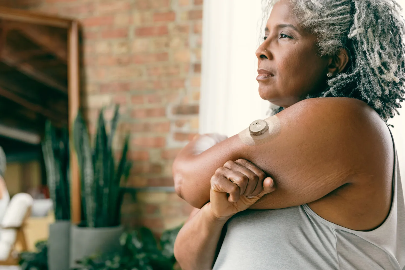 A woman stretches her left shoulder wearing Nutrisense CGM tracking device on her upper left hand available in nutrisense.io