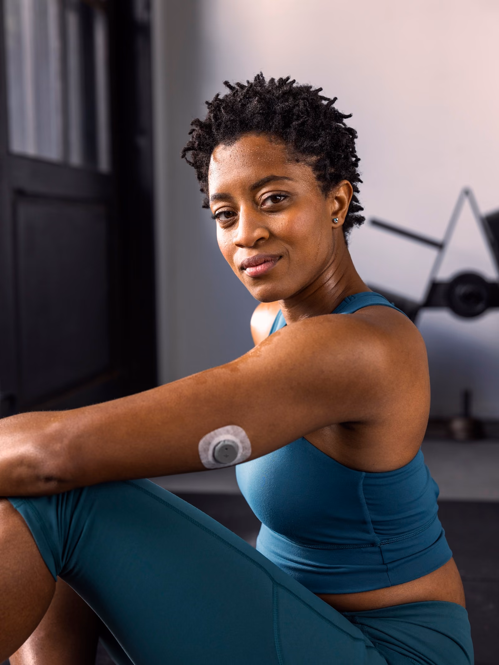 A woman stretches her left shoulder wearing Nutrisense CGM tracking device on her upper left hand available in nutrisense.io