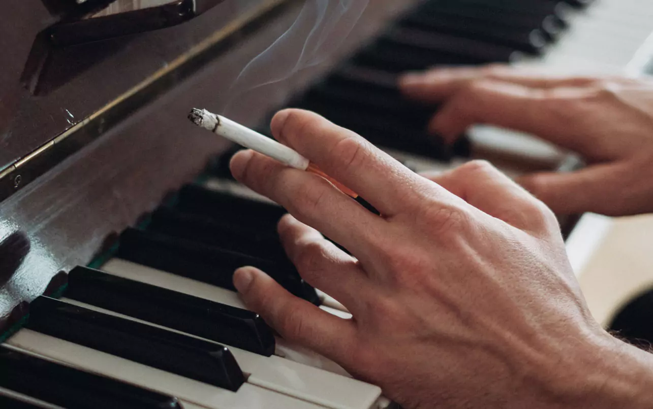 a person smoking and playing the piano