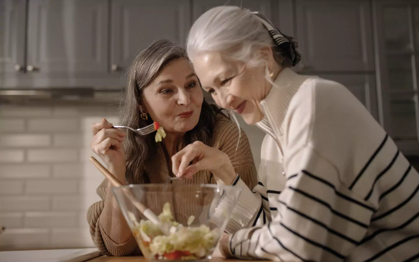 two older people eating a salad 