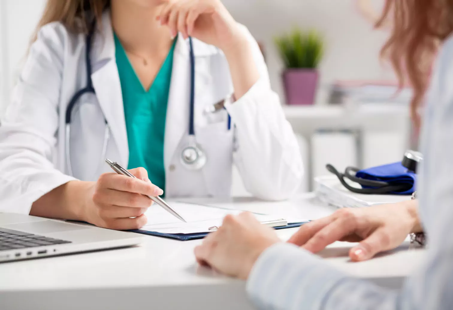 a doctor talking notes and talking to a patient 