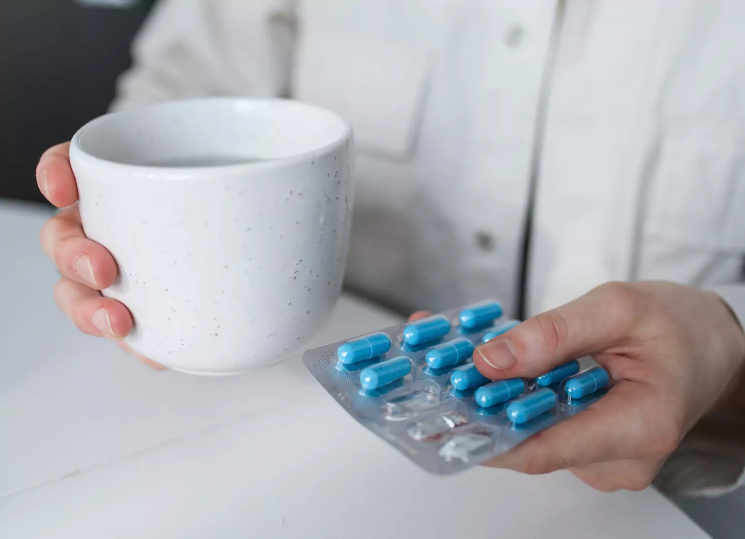 a person holding a cup of water and medicine