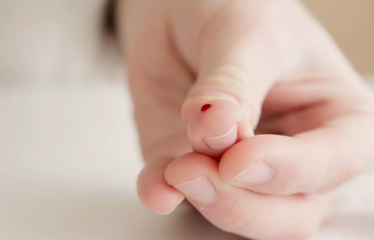 a person using finger prick method to test their glucose level