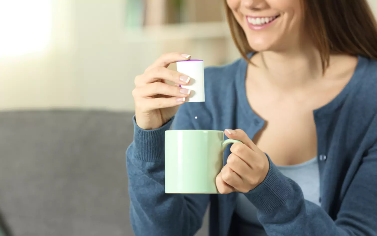 a person adding an artificial sweetener to their drink