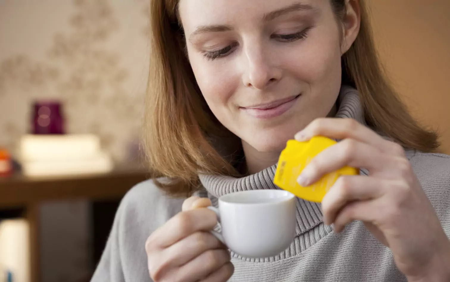 a person adding an artificial sweetener to their drink