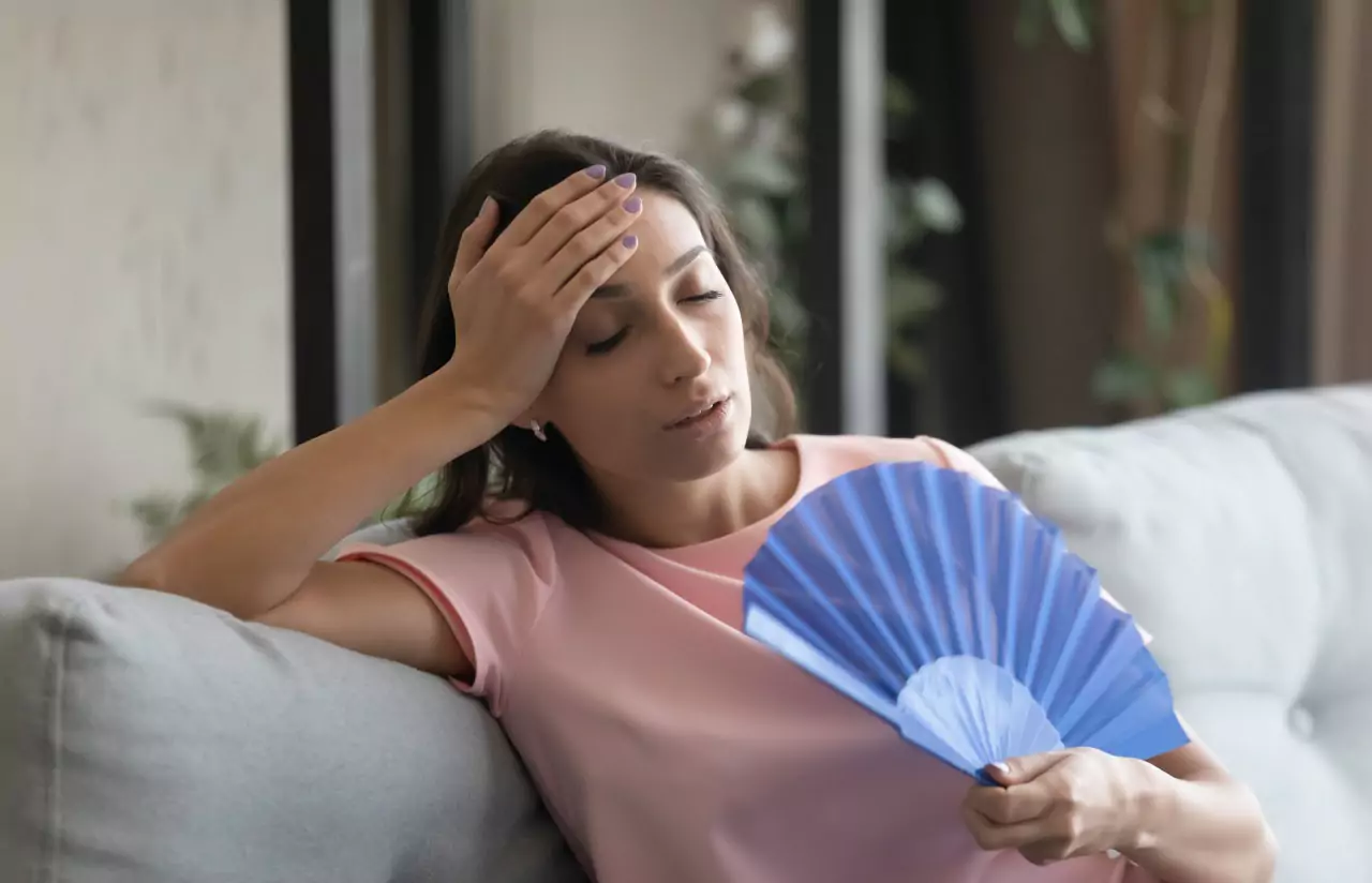 A person on a sofa fanning themselves with a handfan