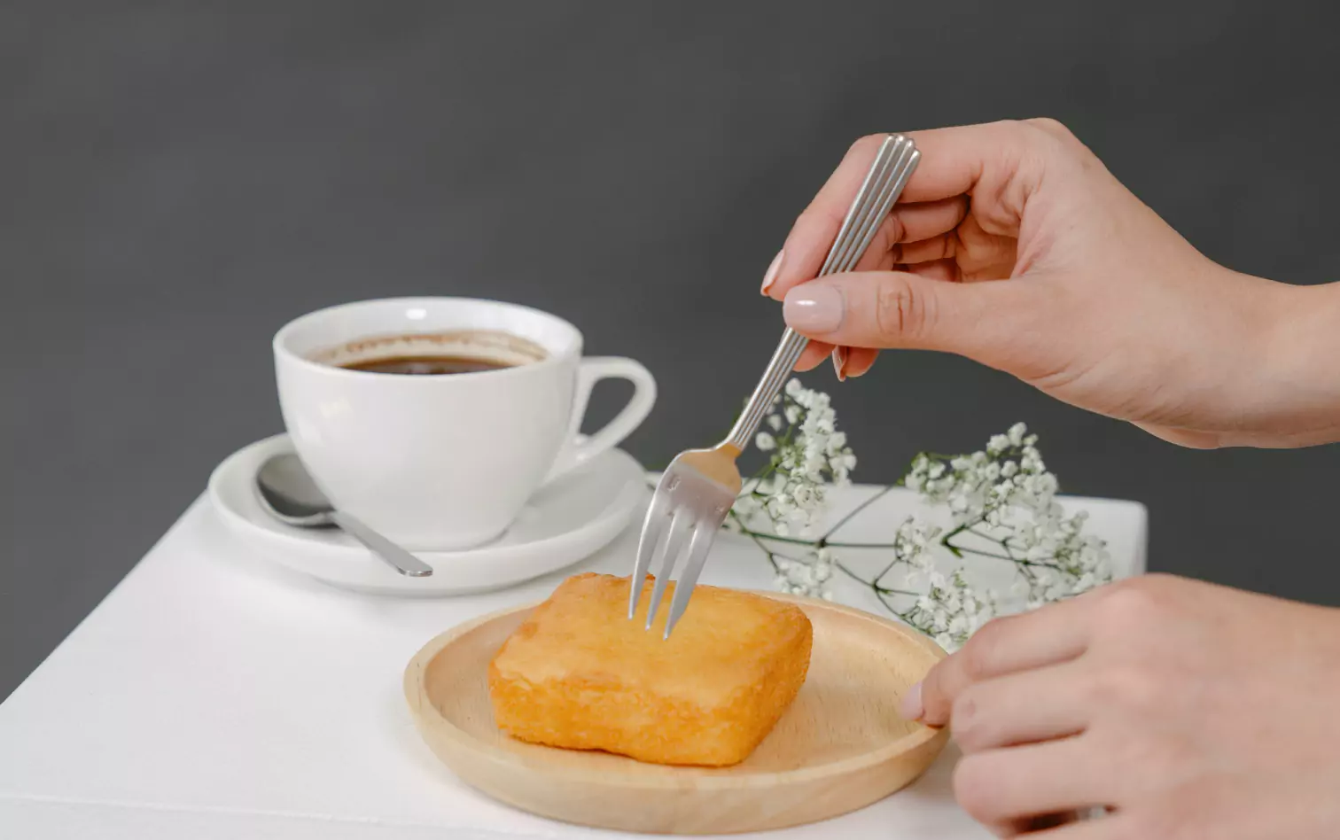 a person eating a biscuit and drinking coffee