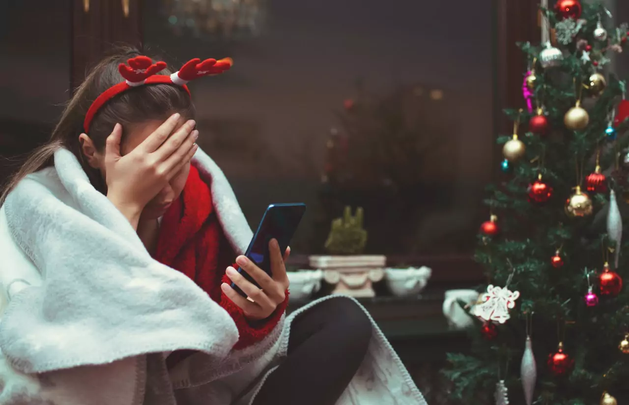 a person sitting near Christmas tree and having a headache 