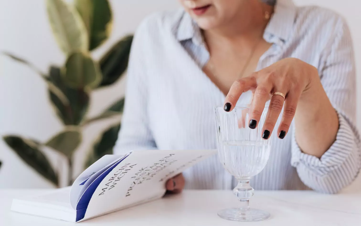 a person holding a glass of water while reading a book