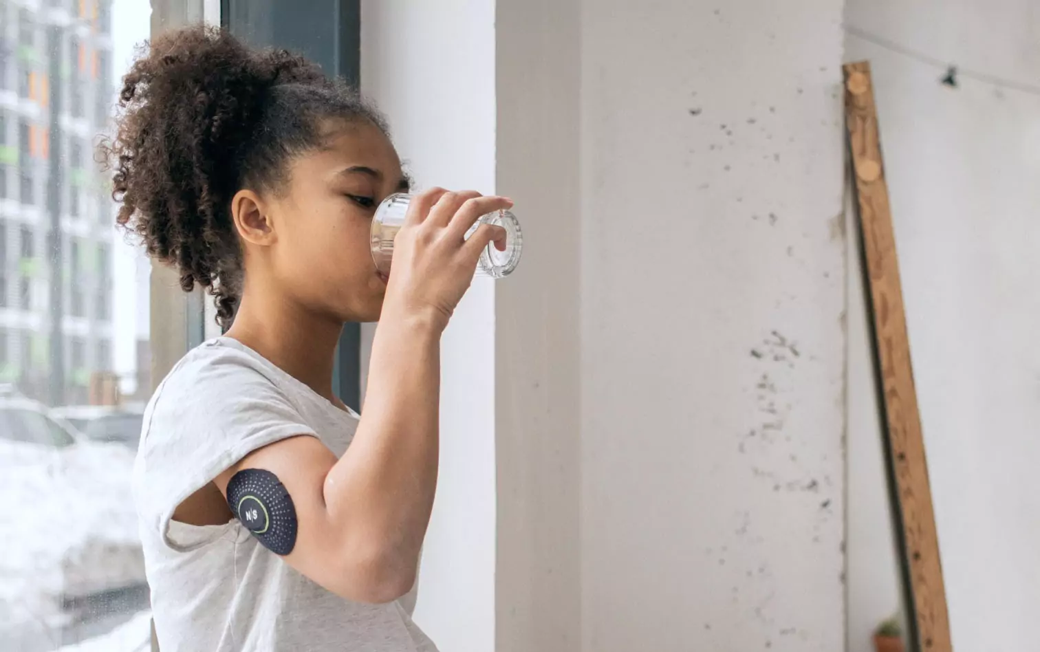 A person drinking water wearing the Nutrisense CGM patch