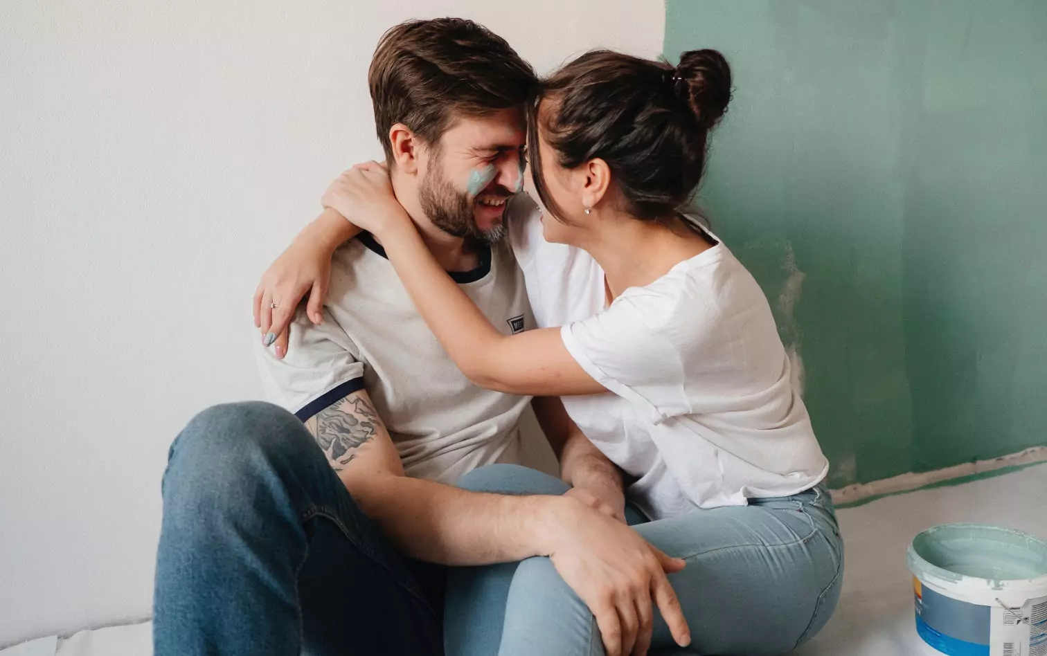 A couple taking a break from painting a room, holding each other and laughing