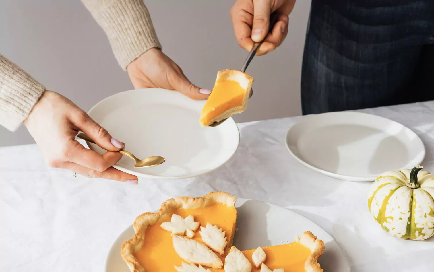 A closeup of hands ver a plate serving pumpkin pie