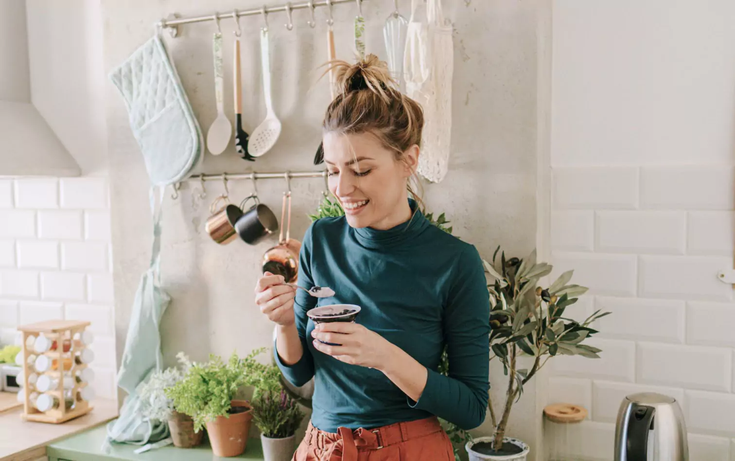 A woman with blonde hair in a kitchen eating yogurt