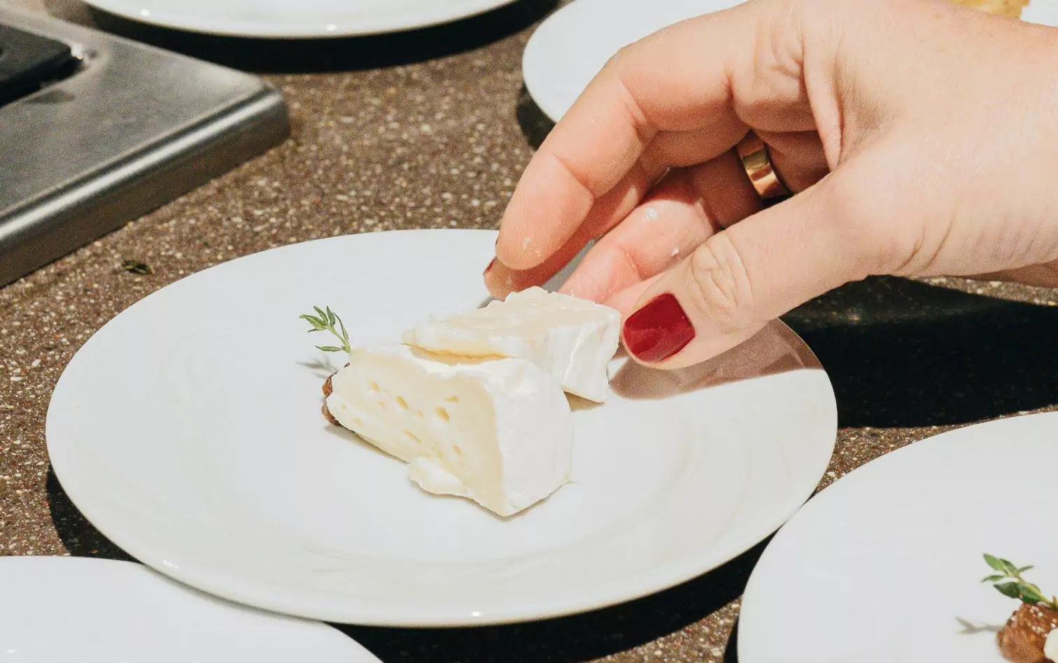 A person holding brie over a white plate