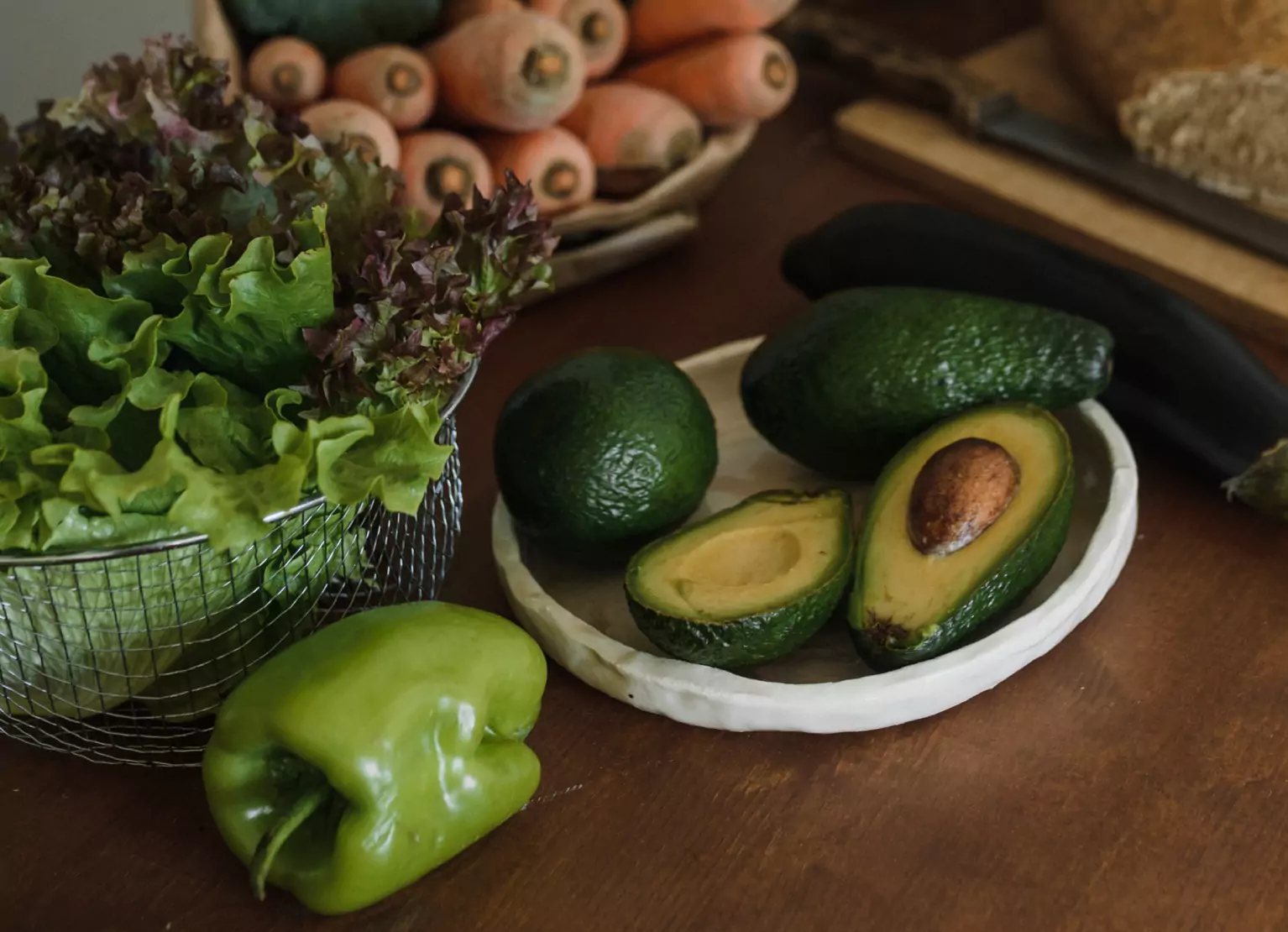 bowl of leafy greens, an avocado and a bell pepper