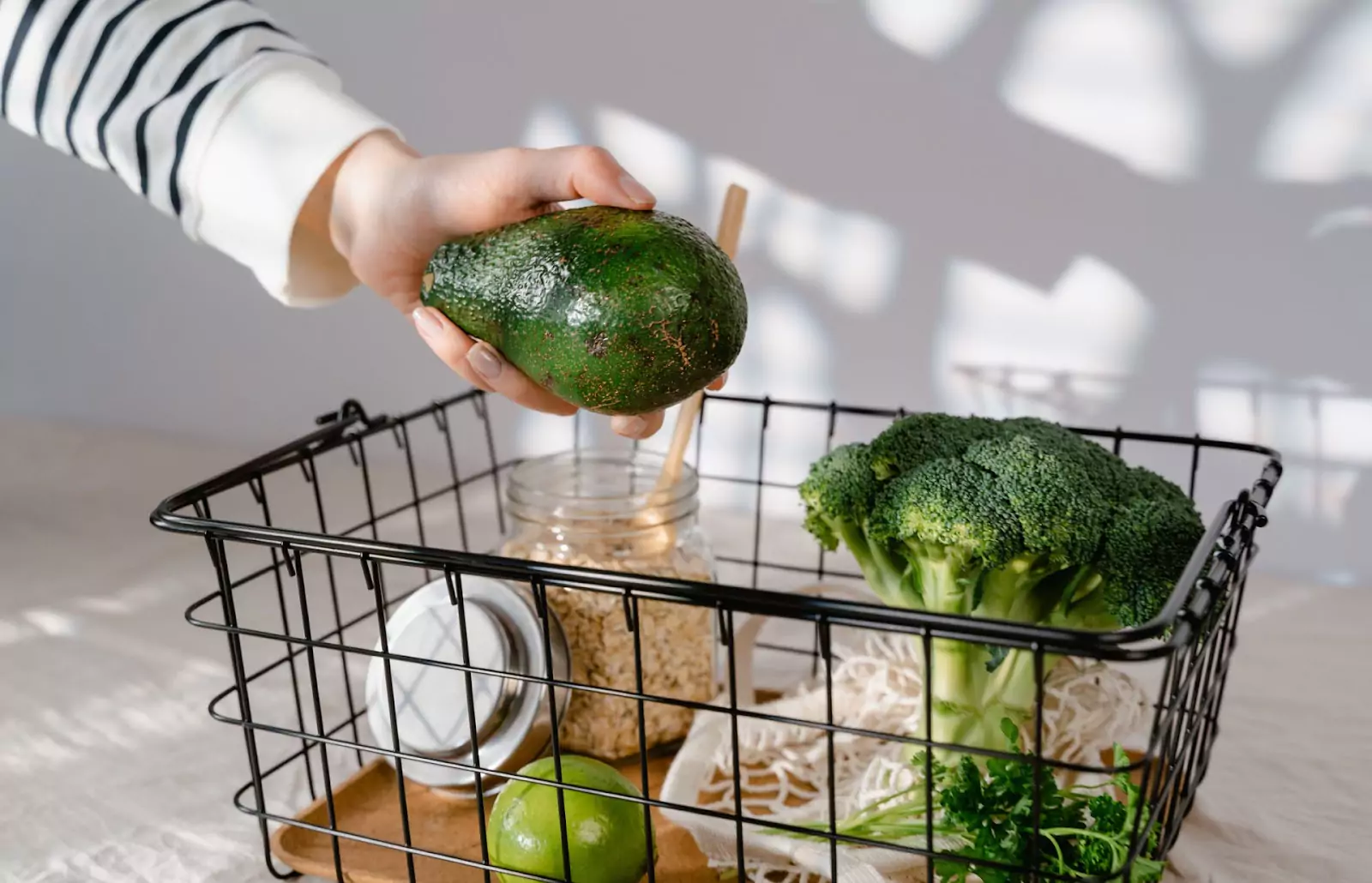 someone putting an avocado in a grocery tray 