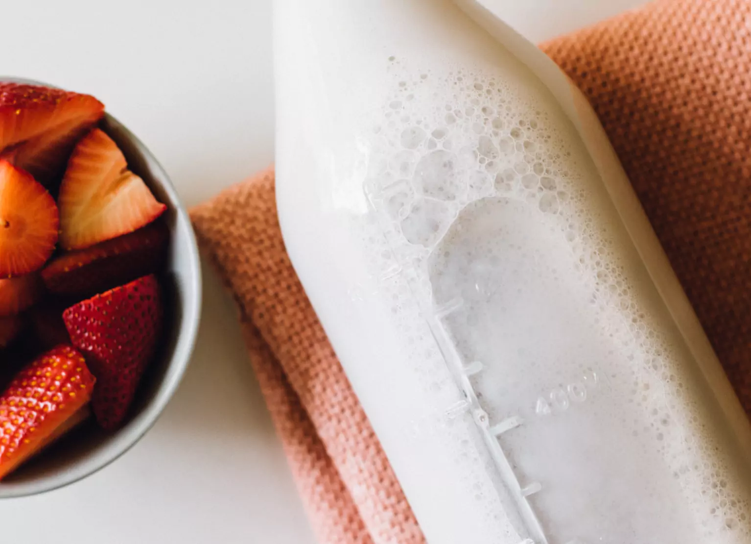 A bottle of kefir with a bowl of strawberries