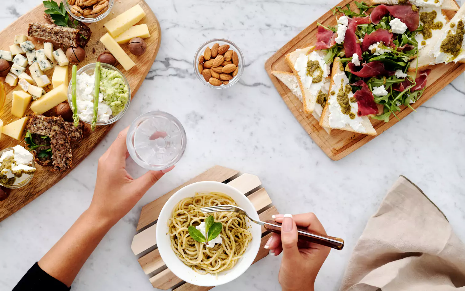 a bowl of pasta and two wooden board of different types of cheese, sandwiches 