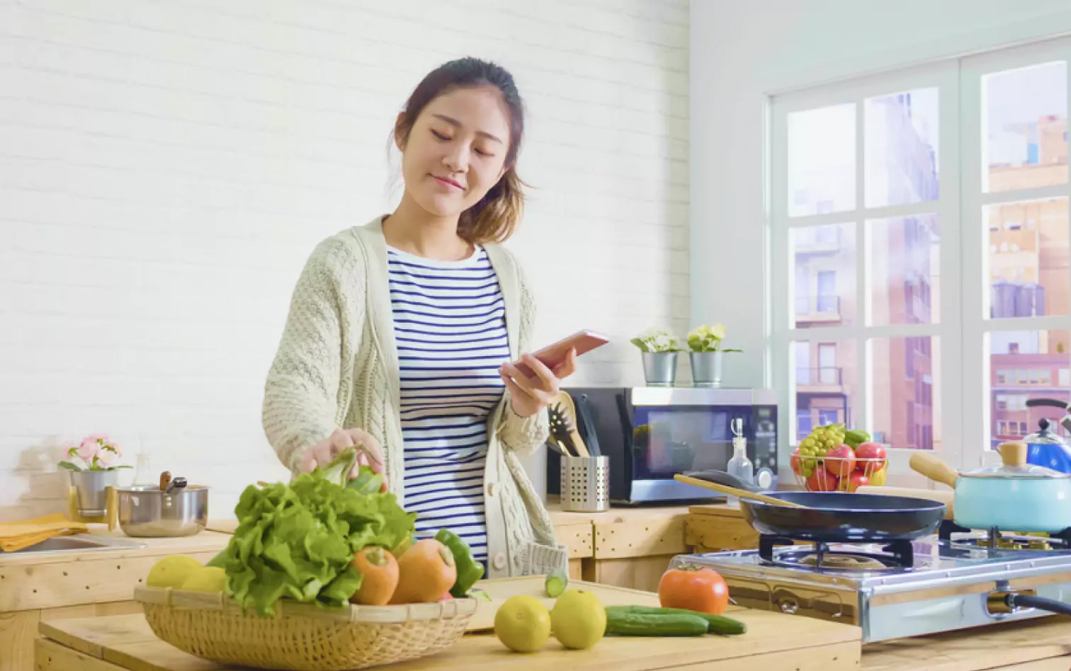 a person standing and holding their phone in the kitchen