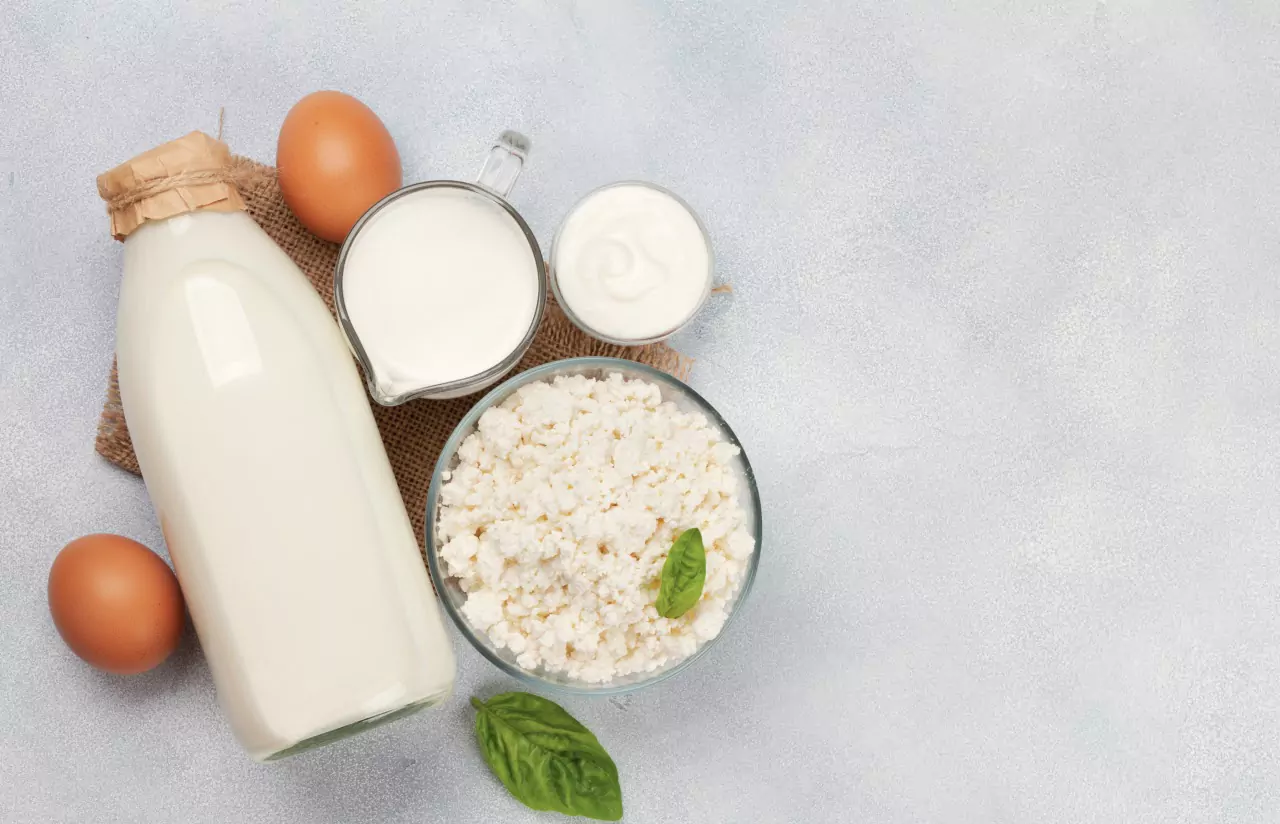 a glass jar of milk, brown eggs, a measuring jug of milk, a cup of cream and fermented milk