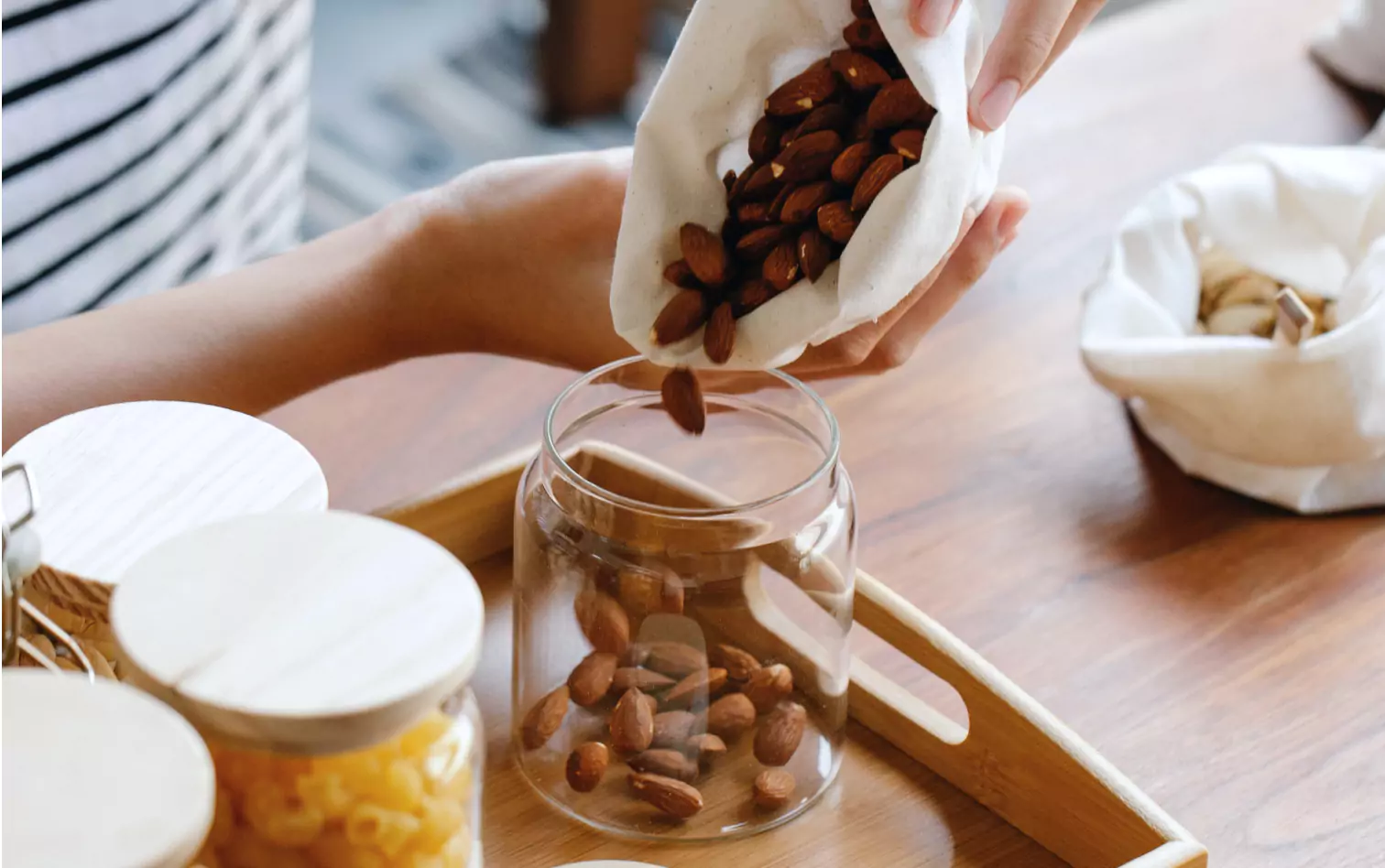 a person pouring almonds into a jar 