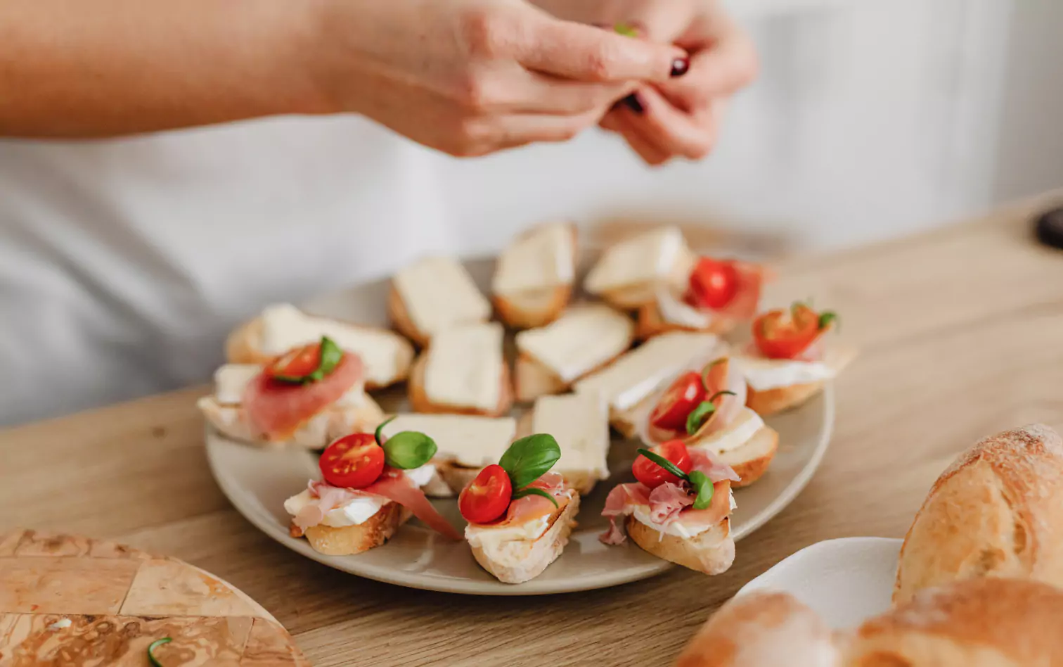 a person making toasts with met, cheese and tomatoes 