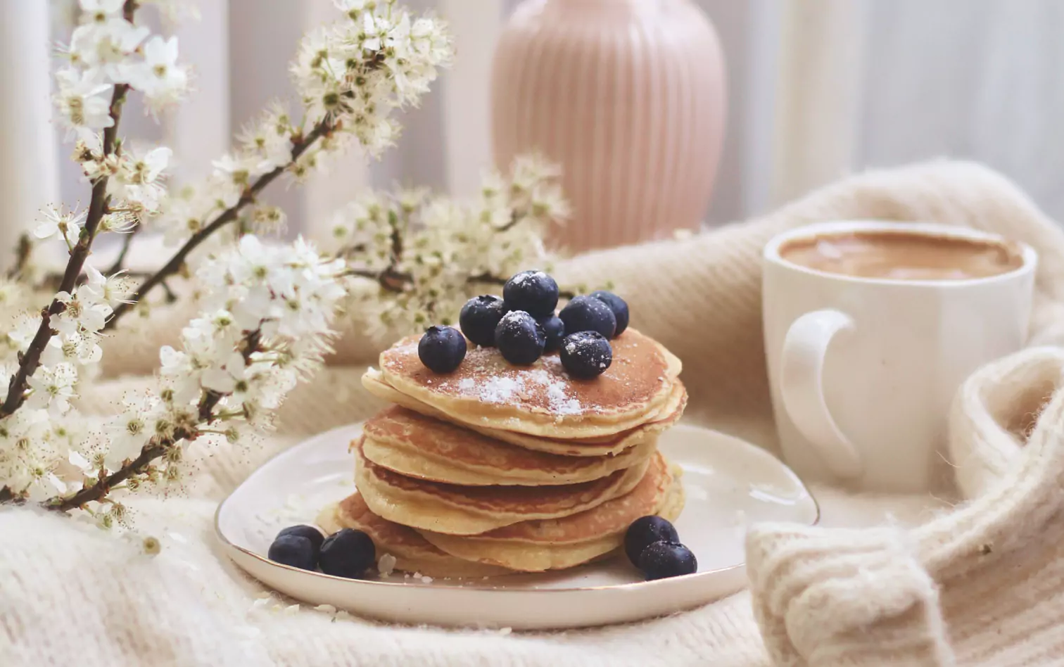 pancakes and blueberries on a plate and a cup of coffee