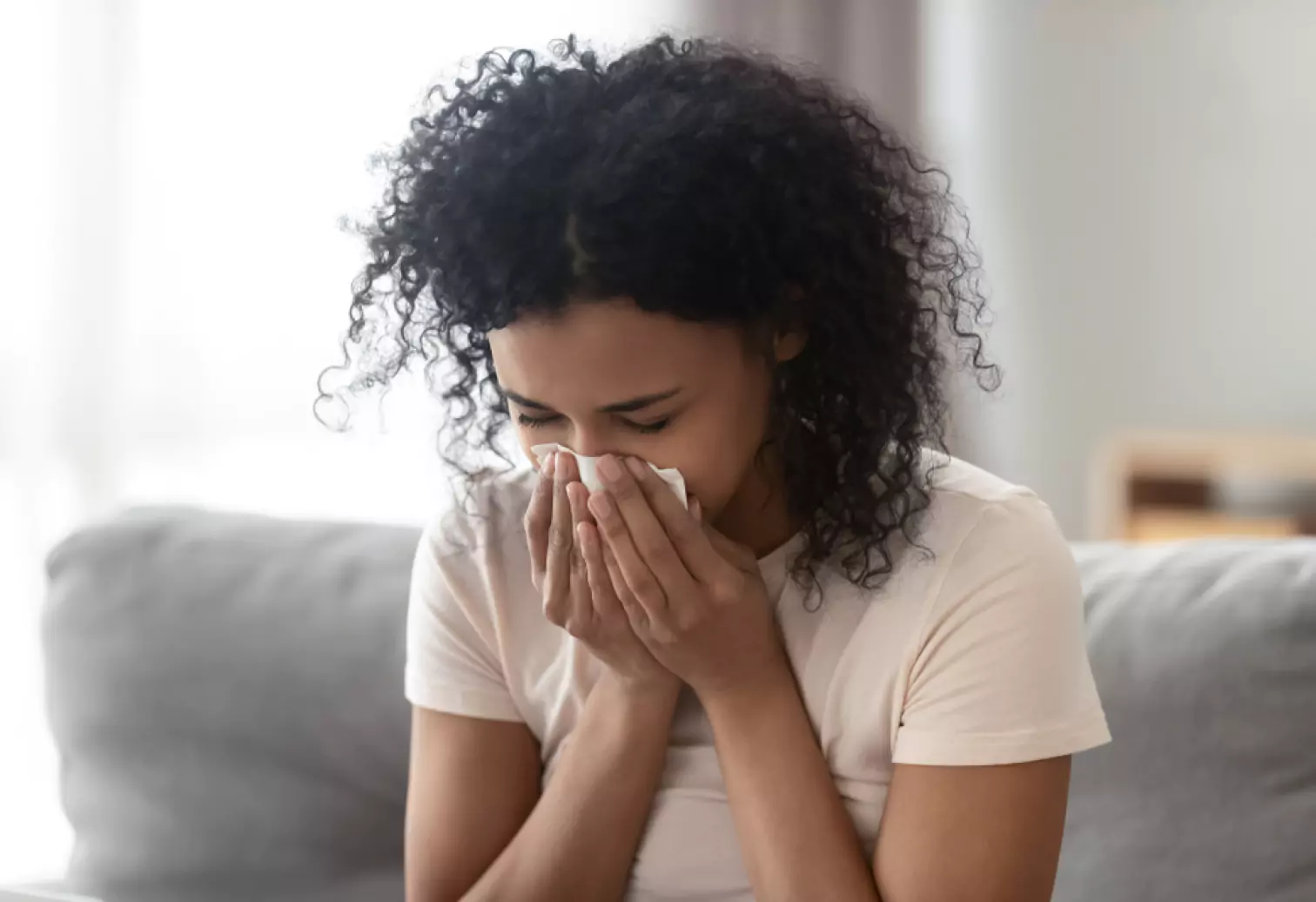 a person sitting on a sofa and sneezing 