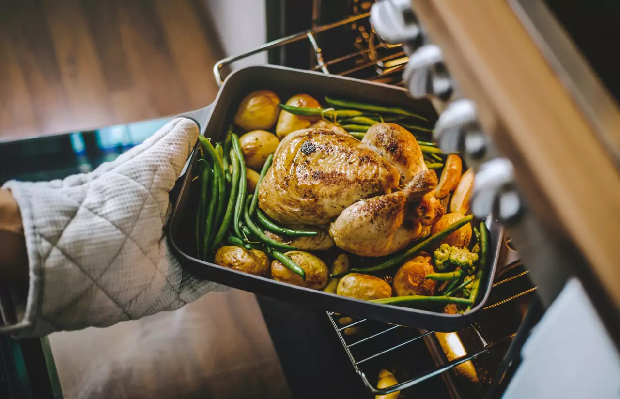 a person roasting a chicken with veggies 