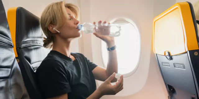 a person sitting and drinking water in the plane