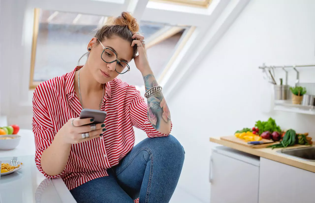 A person looking at a smartphone in the kitchen