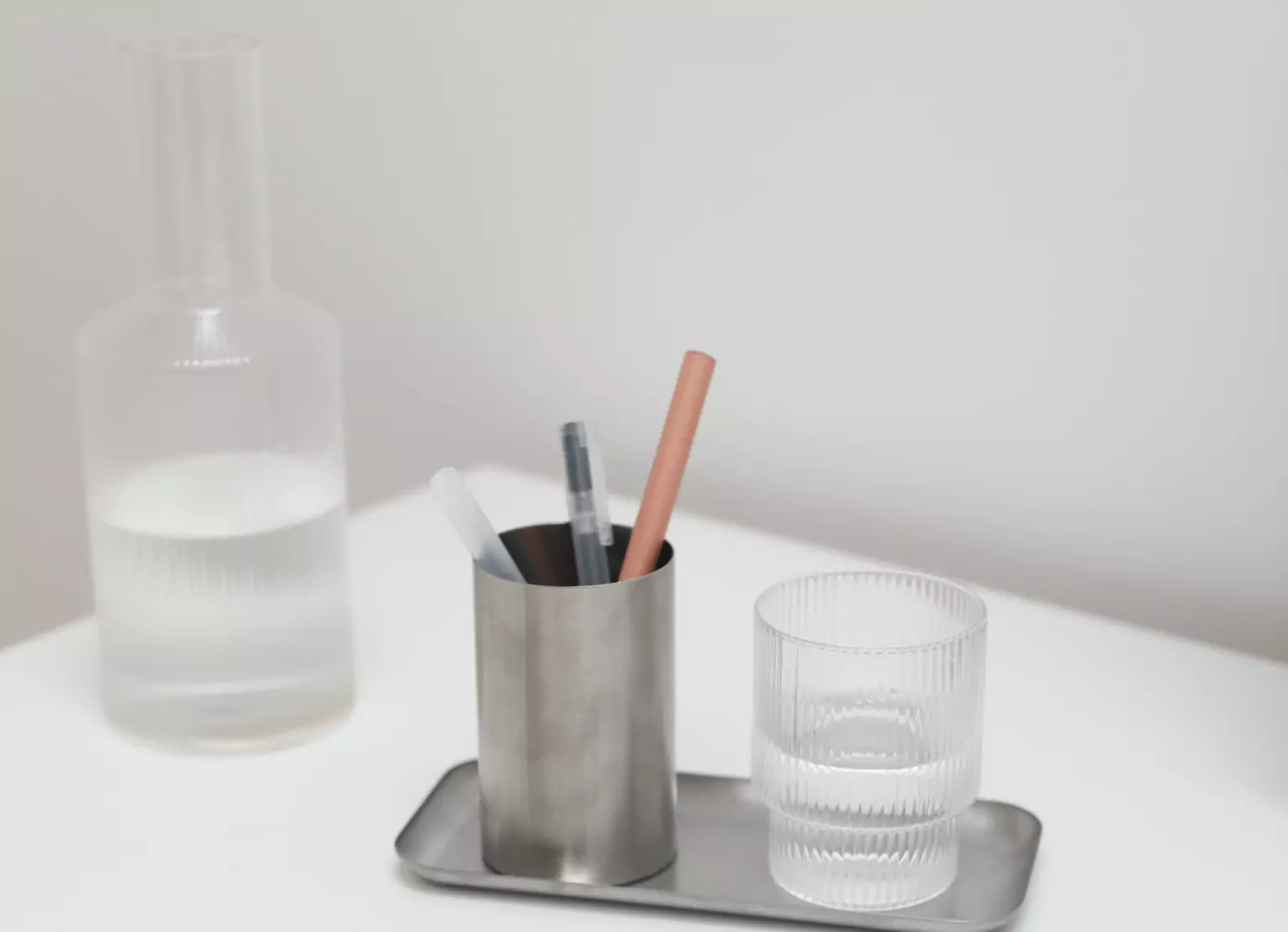 Table with glass of water, pitcher, and pens