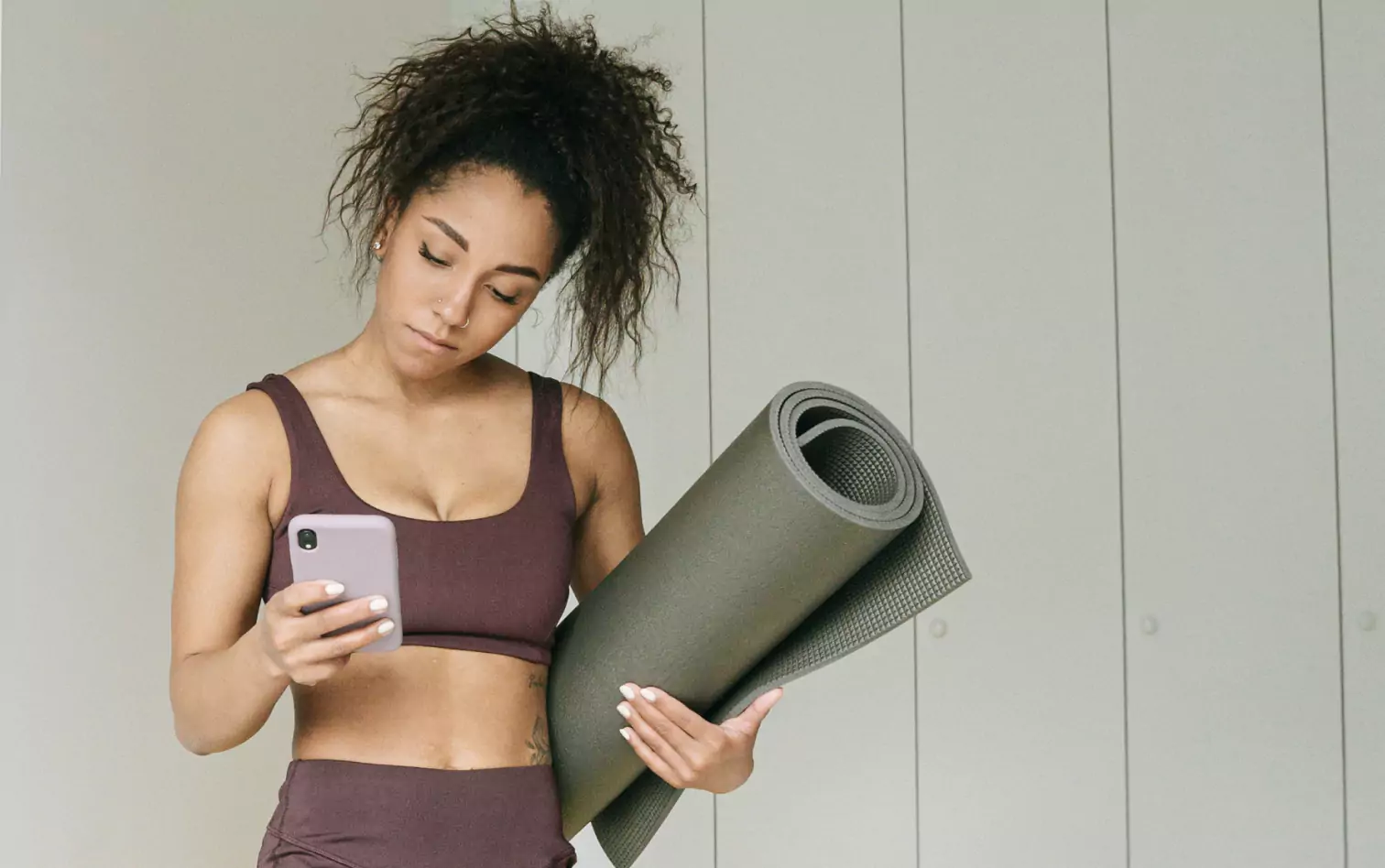 a person holding a yoga mat and looking at their phone