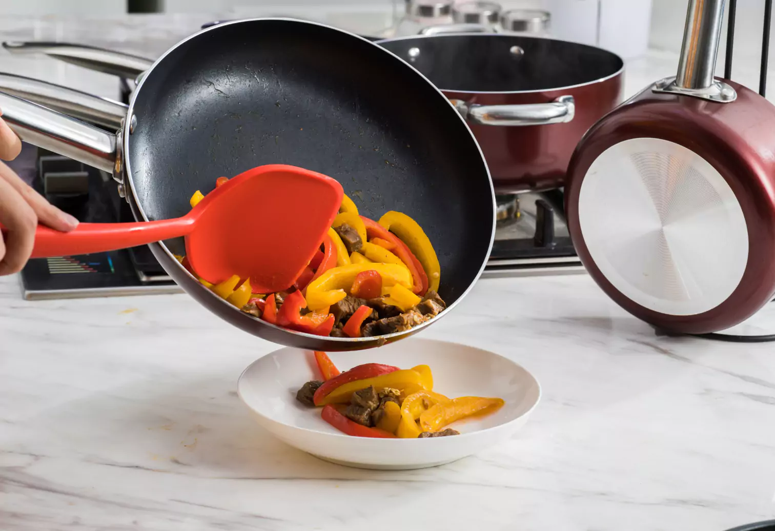 a person pouring meat and veggies from a frying pan in a plate 