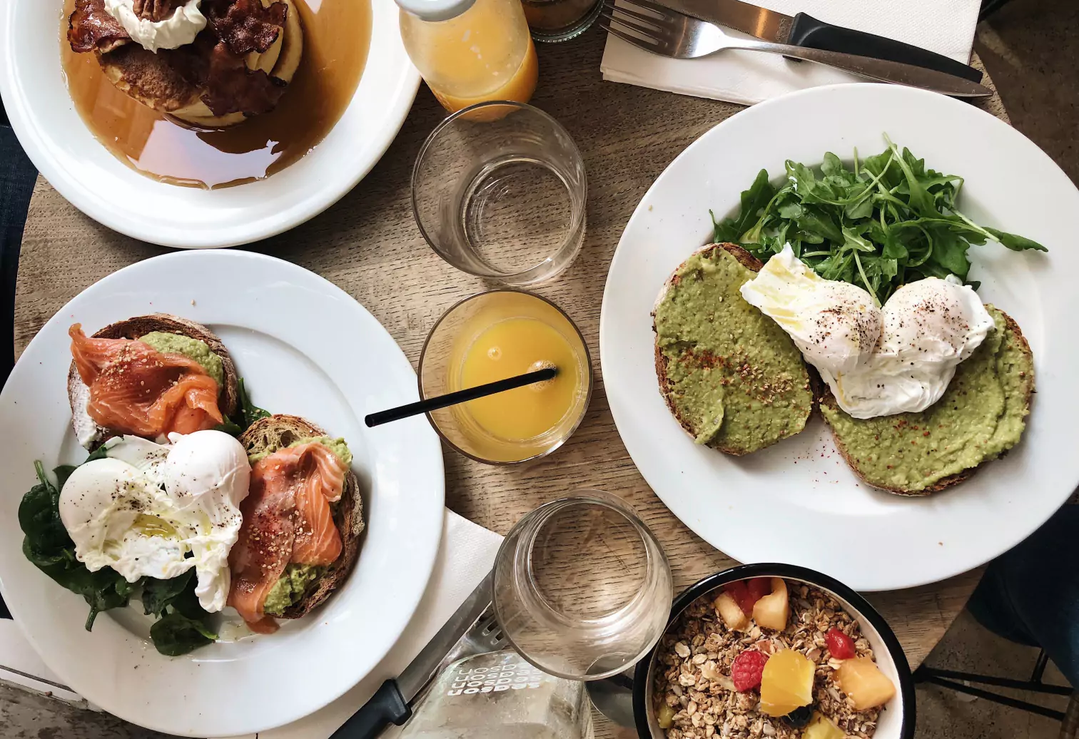 a plates of salmon and avocado toasts and a glass of orange juice 