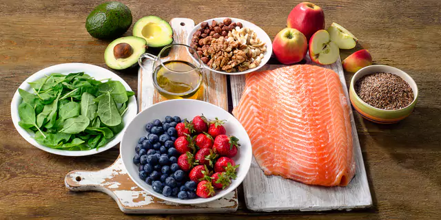 avocados, apples, a bowl of berries, a bowl of nuts and fish