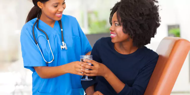 a doctor giving a glass of water to a person 