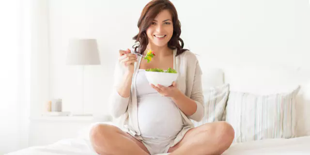 a pregnant woman eating a salad