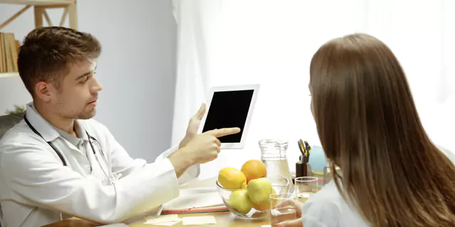 a doctor showing something om a table to patient 