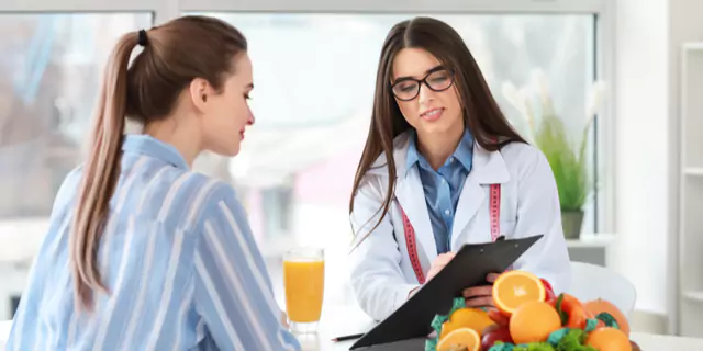 a dietitian showing something on a tablet to a person 