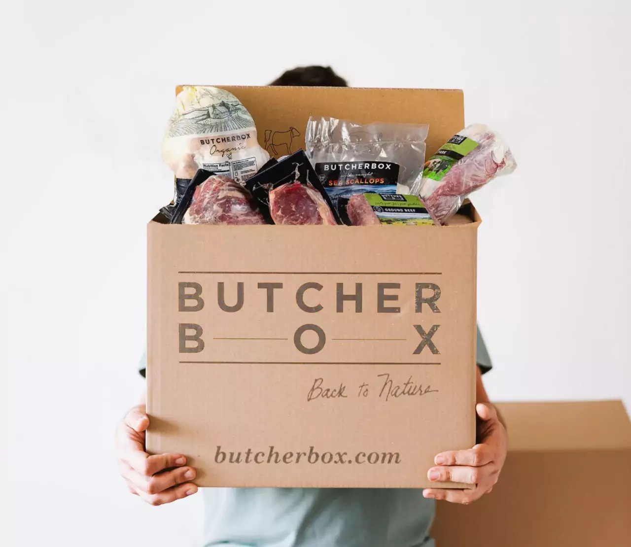 a person holding a Butcher Box full of meat