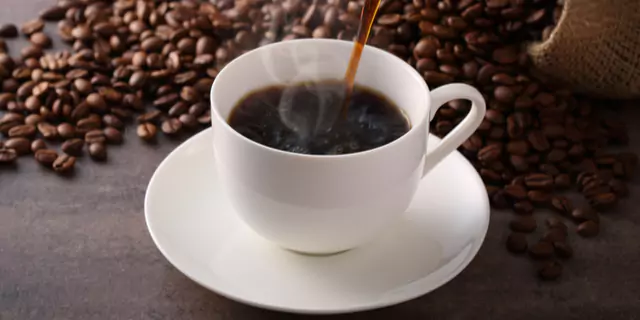 someone pouring black coffee in a cup 