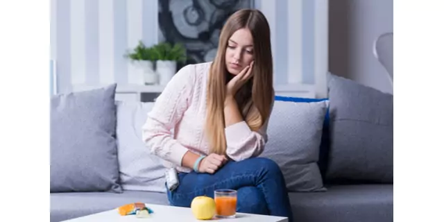 a person siting on a sofa and looking at a glass of juice f